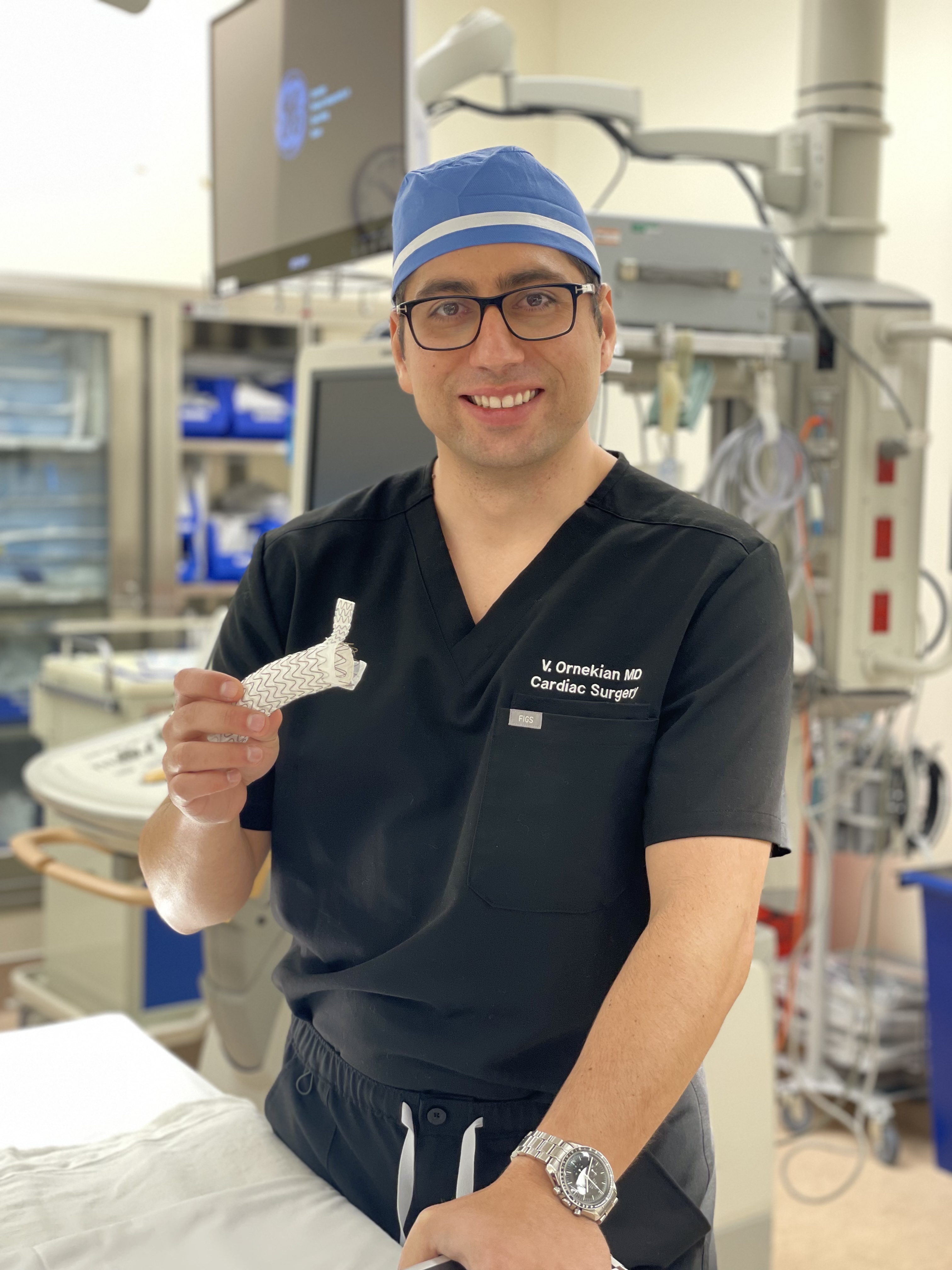 Dr. Ornekian in the operating room holding an aortic stent graft